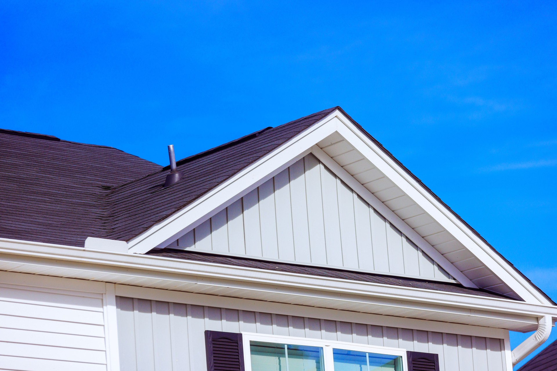 Modern residential roof design showcasing shingles, siding under clear blue sky