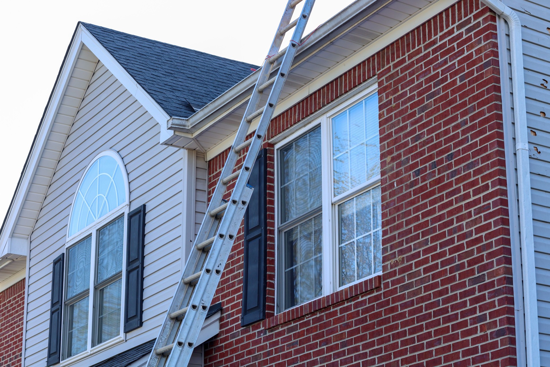 Metal ladder leans against the roof of the house